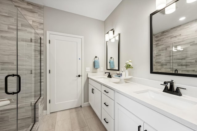 bathroom with a sink, a shower stall, and double vanity