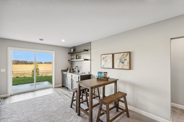 dining space with wet bar, light wood-style flooring, baseboards, and wine cooler