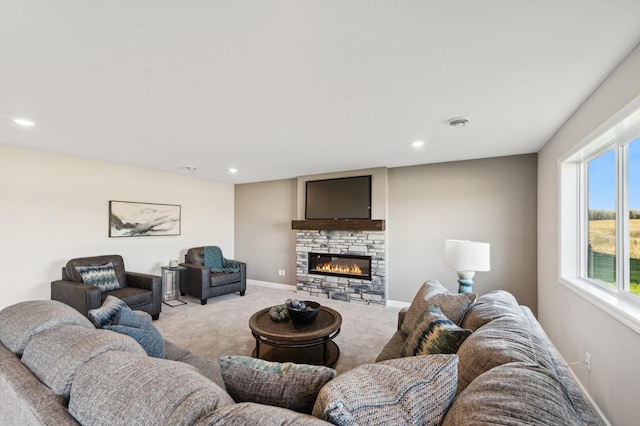 living area featuring baseboards, a stone fireplace, recessed lighting, and light colored carpet