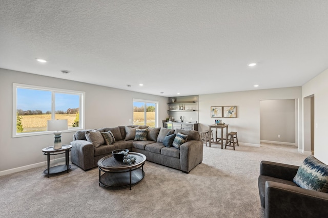 living area featuring recessed lighting, light carpet, a textured ceiling, and baseboards