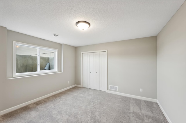 unfurnished bedroom featuring baseboards, a closet, visible vents, and carpet flooring