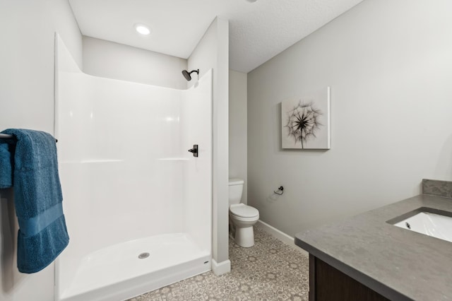 bathroom featuring a shower, baseboards, vanity, and toilet