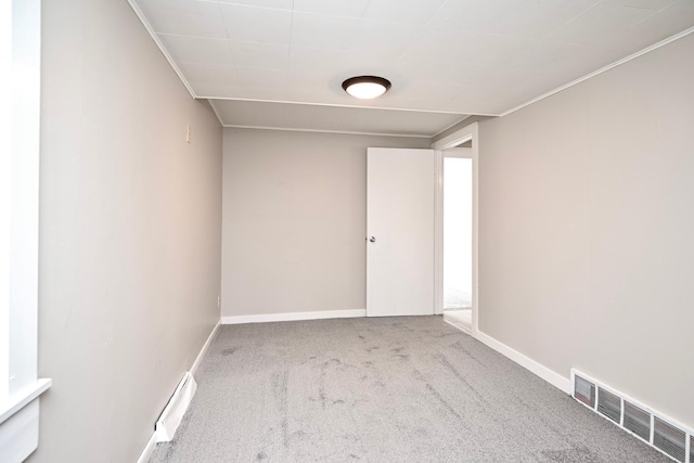 spare room with carpet, crown molding, visible vents, and baseboards