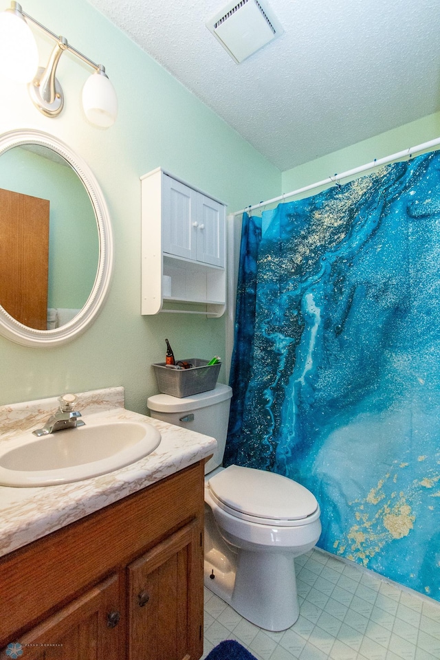 bathroom featuring a textured ceiling, toilet, vanity, and visible vents