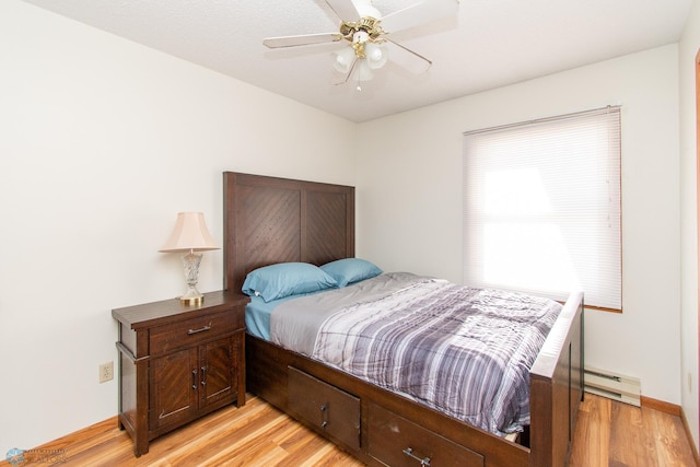 bedroom with a baseboard heating unit, ceiling fan, light wood-style flooring, and baseboards