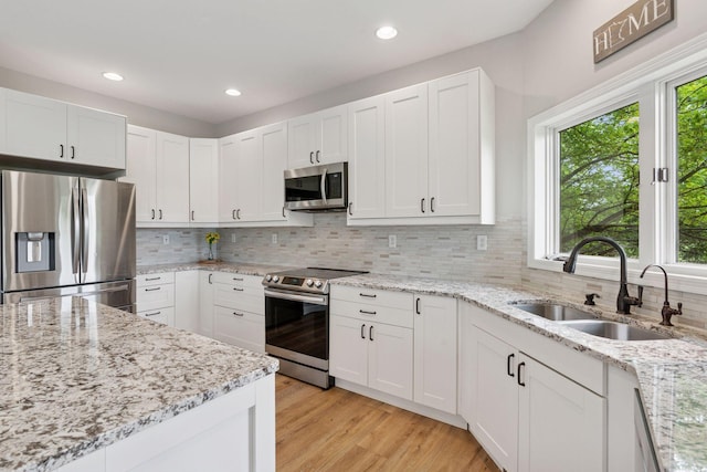 13380 Willandale Rd, Rogers, MN 55374 - kitchen featuring stainless steel appliances, a sink, white cabinetry, tasteful backsplash, and light wood-style floors