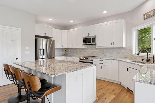 13380 Willandale Rd, Rogers, MN 55374 - kitchen with appliances with stainless steel finishes, a sink, tasteful backsplash, a center island, and light wood finished floors