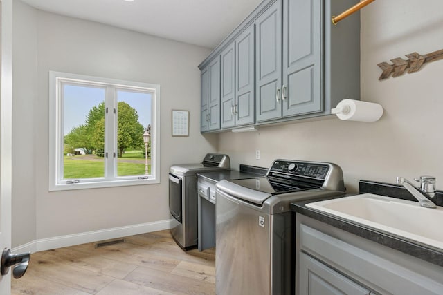 13380 Willandale Rd, Rogers, MN 55374 - laundry area with washing machine and clothes dryer, cabinet space, light wood-type flooring, and baseboards