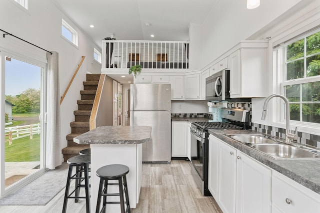 13380 Willandale Rd, Rogers, MN 55374 - kitchen featuring appliances with stainless steel finishes, a sink, plenty of natural light, a towering ceiling, and a center island
