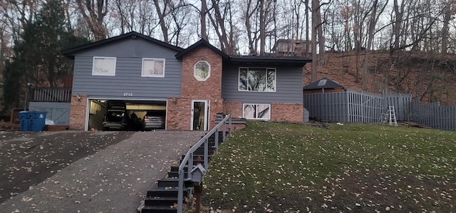 view of front facade featuring a garage, brick siding, fence, driveway, and a front yard