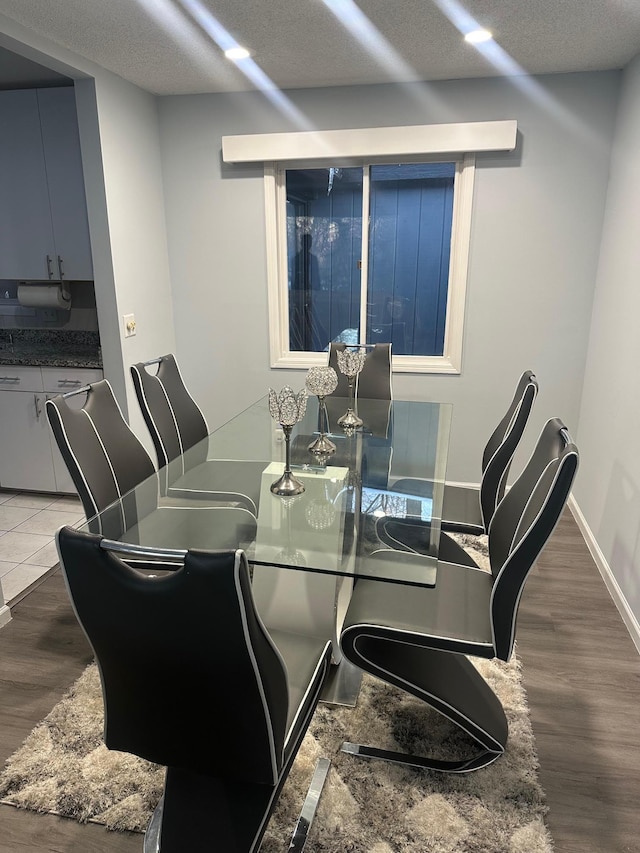 dining area with a textured ceiling, baseboards, and wood finished floors