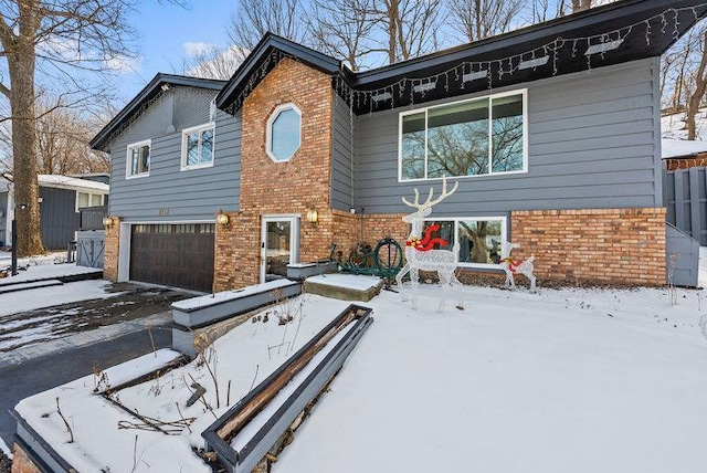 view of front facade with a garage, driveway, and brick siding