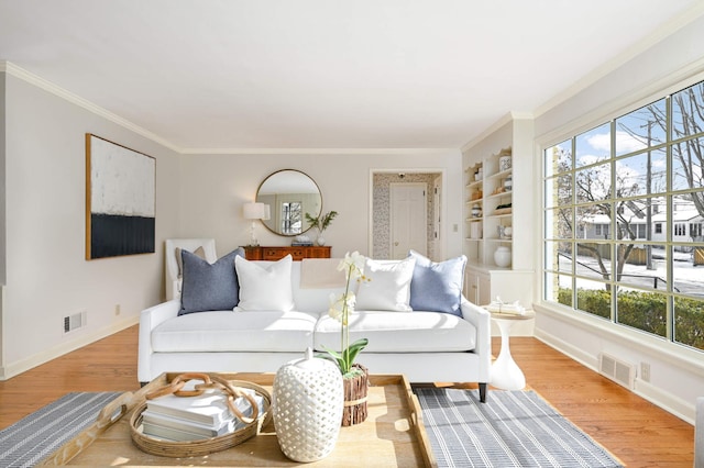 living area featuring light wood-style floors, visible vents, crown molding, and baseboards