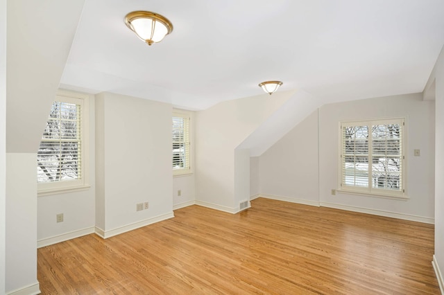 bonus room featuring baseboards, light wood-style floors, visible vents, and a healthy amount of sunlight