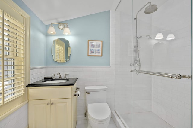 full bath with toilet, a shower stall, tile walls, and wainscoting