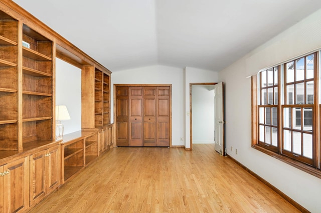 spare room with light wood-type flooring, baseboards, and vaulted ceiling