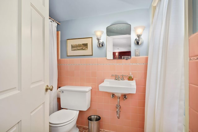 full bathroom with wainscoting, toilet, and tile walls