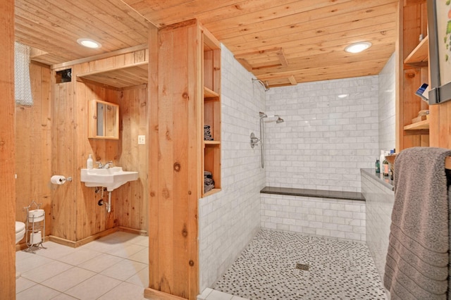 bathroom with toilet, wooden ceiling, a tile shower, and tile patterned flooring