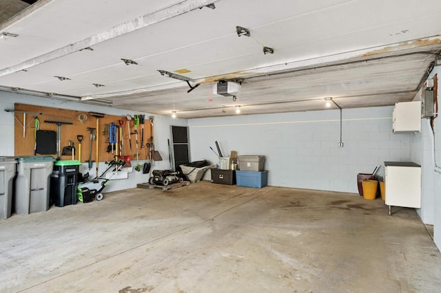 garage with a garage door opener and concrete block wall