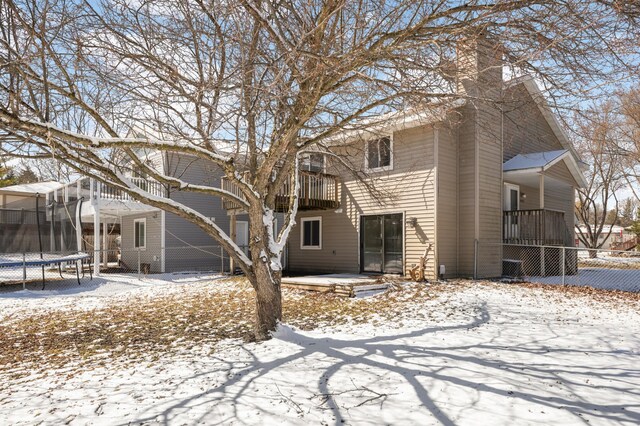 16860 Grenadier Ave, Lakeville, MN 55044 - snow covered house with a balcony, a chimney, fence, and a trampoline