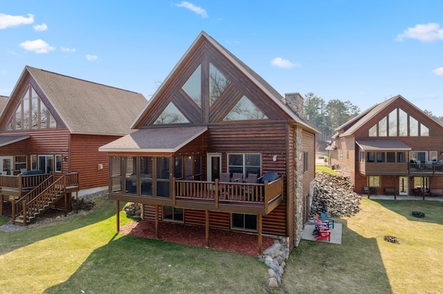 rear view of house with a chimney, stairway, a deck, and a yard