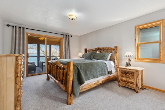 bedroom featuring access to exterior, carpet, baseboards, and a textured ceiling