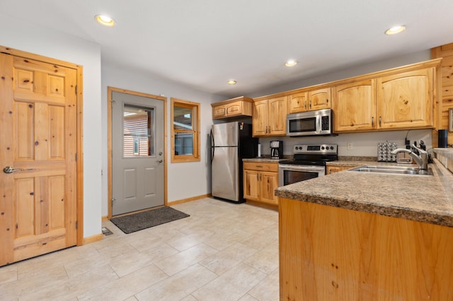 kitchen featuring appliances with stainless steel finishes, dark countertops, a sink, and recessed lighting