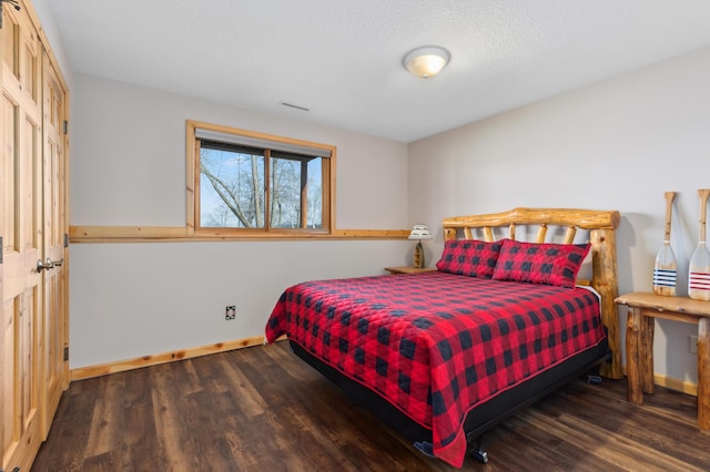 bedroom with dark wood-style flooring, visible vents, and baseboards