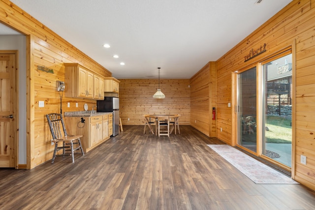 kitchen featuring light stone counters, dark wood-type flooring, decorative light fixtures, and freestanding refrigerator