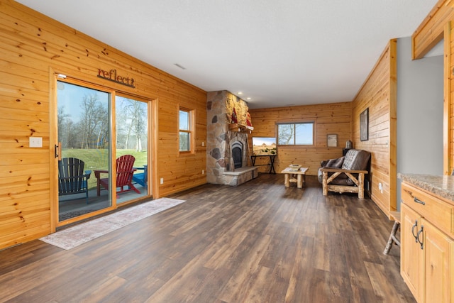 living area with dark wood-type flooring, wood walls, and a fireplace