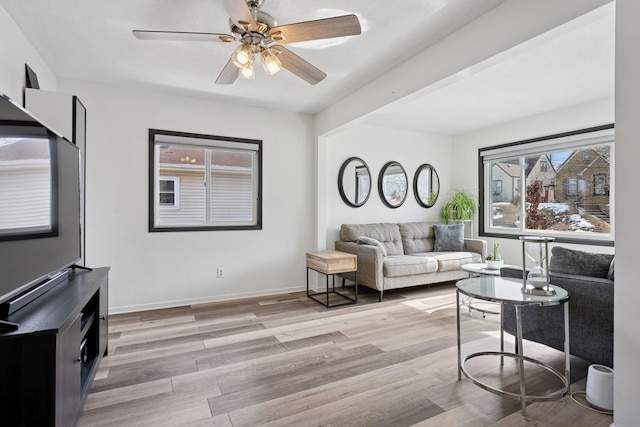 living area featuring a ceiling fan, light wood-style floors, and baseboards