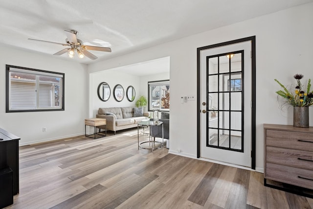 interior space with a ceiling fan, baseboards, and wood finished floors