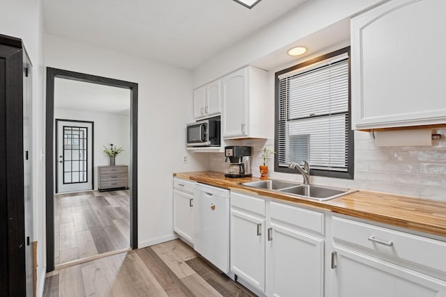 kitchen featuring wood counters, stainless steel microwave, white dishwasher, and a sink