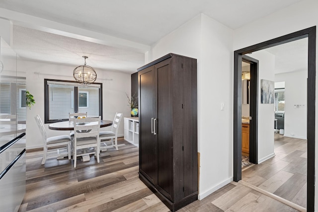 dining room with a chandelier, light wood-style flooring, and baseboards