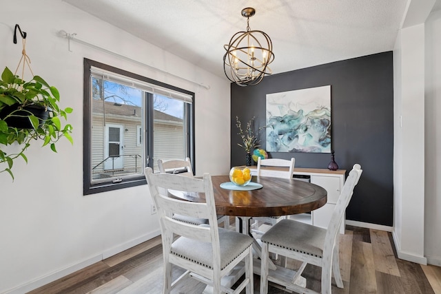 dining space featuring baseboards, an inviting chandelier, and wood finished floors