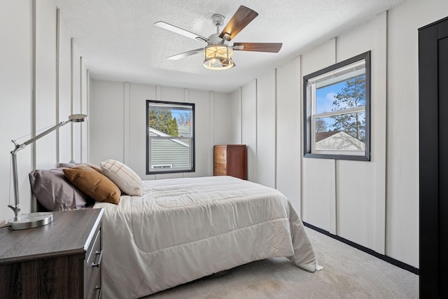 bedroom with a decorative wall, multiple windows, a textured ceiling, and carpet