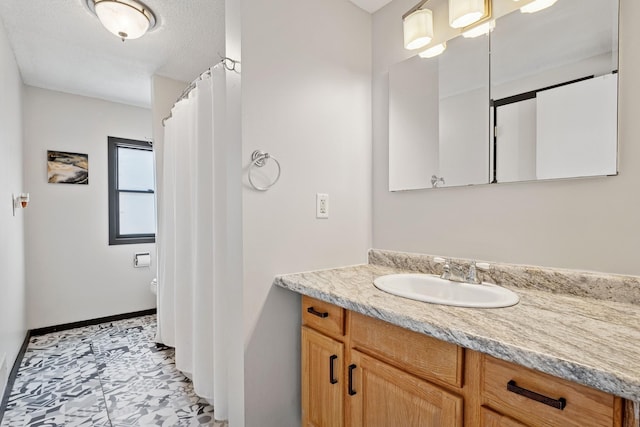 bathroom with vanity, toilet, and baseboards