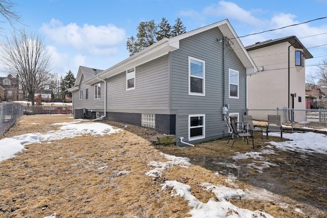 view of snow covered exterior with central AC unit and a fenced backyard