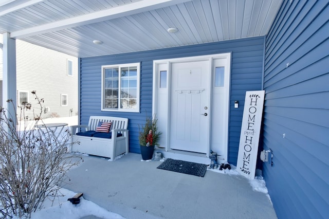 snow covered property entrance with a porch