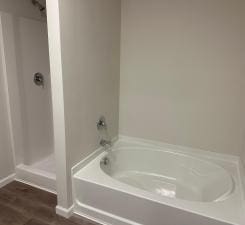 full bath featuring a shower, wood finished floors, and a bath