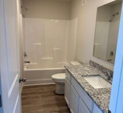 full bathroom with washtub / shower combination, vanity, toilet, and wood finished floors