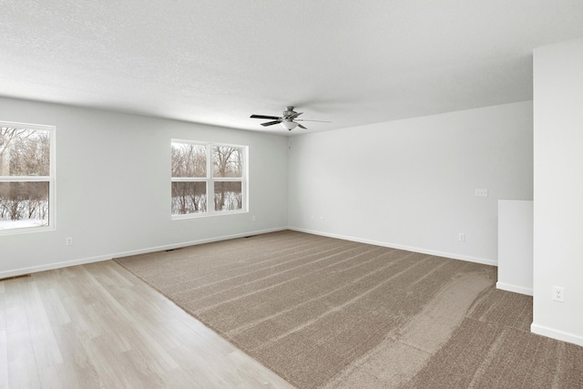 spare room with a textured ceiling, ceiling fan, and baseboards