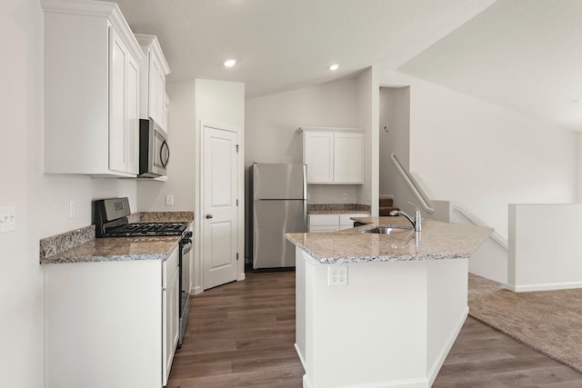 kitchen featuring a center island with sink, a sink, white cabinetry, stainless steel appliances, and vaulted ceiling