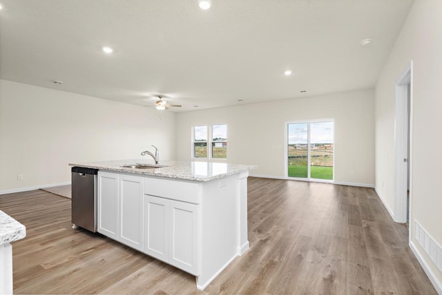 kitchen with a sink, a kitchen island with sink, dishwasher, and open floor plan