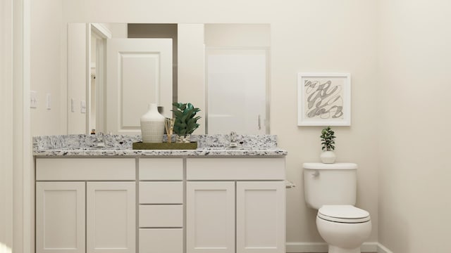 bathroom with double vanity, toilet, baseboards, and a sink