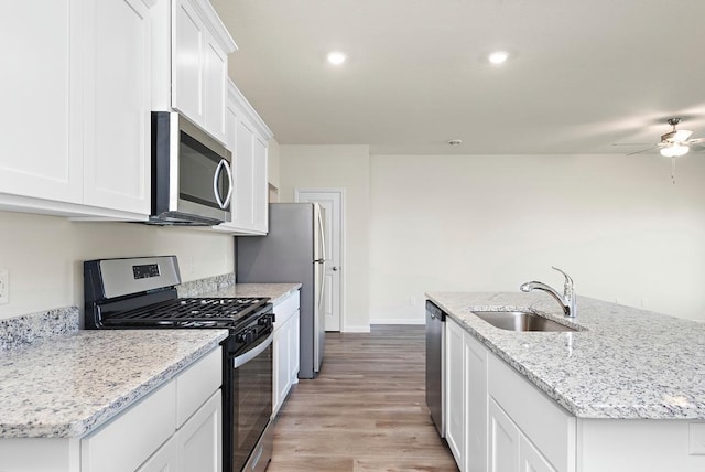 kitchen with appliances with stainless steel finishes, a kitchen island with sink, white cabinetry, and a sink