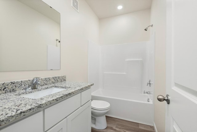 full bath featuring shower / washtub combination, visible vents, toilet, vanity, and wood finished floors