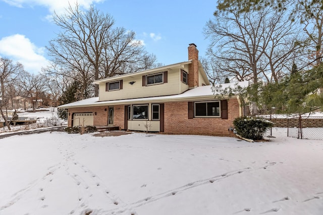 traditional-style house featuring an attached garage, a chimney, and brick siding