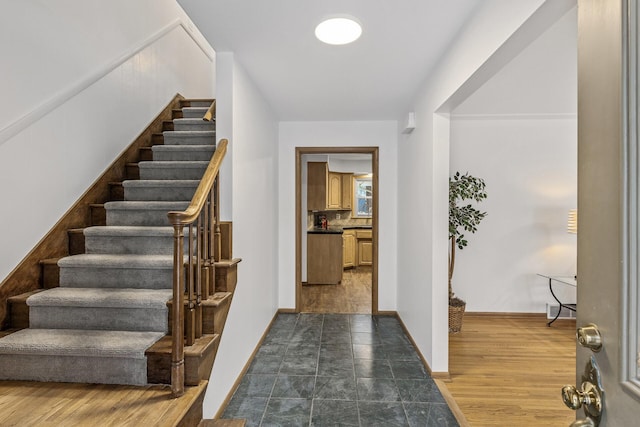 entrance foyer with dark wood-type flooring, stairway, and baseboards