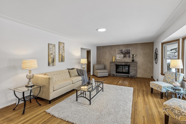 living area with a stone fireplace and wood finished floors